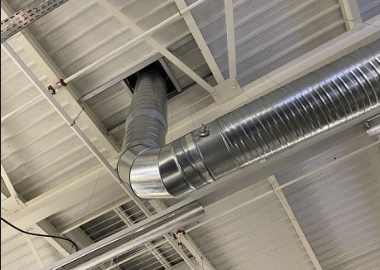 Réseau de gaines de ventilation double flux sous la toiture d’un bâtiment commercial